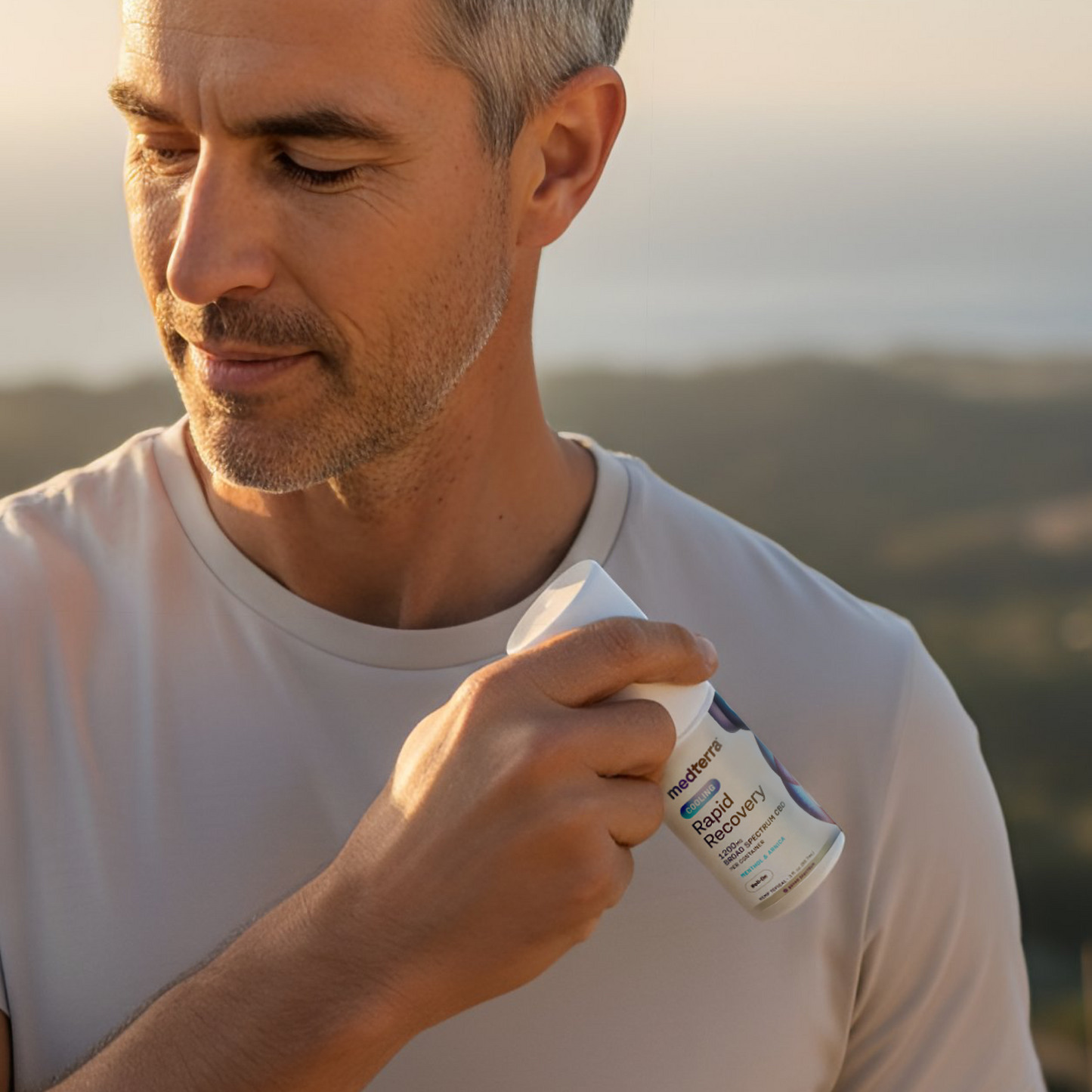Man applying medterra Rapid Recovery Cooling Broad Spectrum CBD roll-on to his shoulder